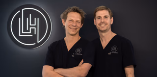 Photo of two dentists in front of a logo